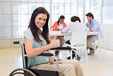 Attractive businesswoman in wheelchair gives thumbs up to camera