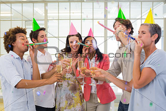 Casual business team celebrating with champagne and party horns
