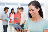 Attractive businesswoman using tablet with coworkers behind
