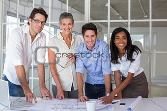 Team of architects going over blueprints smiling at camera