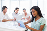 Attractive businesswoman using tablet with coworkers behind