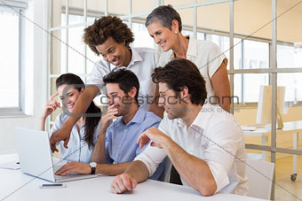 Workers laugh while looking at laptop