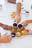 Business people taking muffins from plate