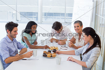 Work colleagues having hot beverages and muffins