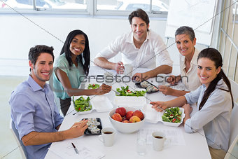 Workers smile at camera while eating healthy lunch