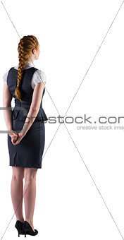 Redhead businesswoman standing with hands behind