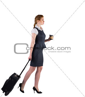 Redhead businesswoman pulling her suitcase holding coffee