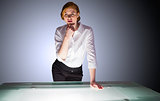 Redhead businesswoman standing and thinking by a desk