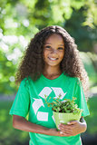 Young environmental activist smiling at the camera holding a potted plant