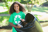 Young environmental activist smiling at the camera picking up trash