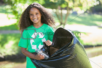 Young environmental activist smiling at the camera picking up trash