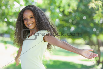 Young girl smiling at the camera with arms outstretched