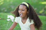 Young girl holding a flower and sneezing in the park