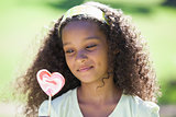 Young girl holding a heart lollipop in the park