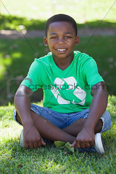 Young boy sitting on grass in recycling tshirt