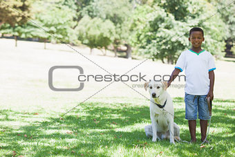 Little boy standing with his pet labrador in the park