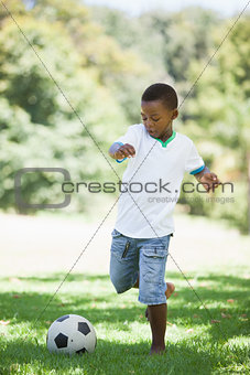Little boy kicking a football in the park
