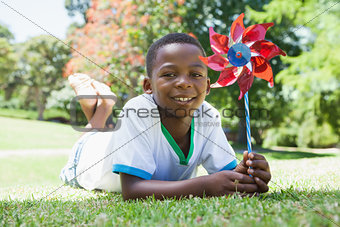 Little boy holding pinwheel in the park smiling at camera