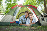 Cute couple lying in their tent smiling at camera