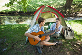 Cute man serenading his girlfriend on camping trip
