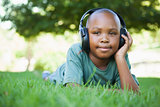 Little boy lying on grass listening to music and smiling