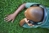 Little boy lying on grass listening to music