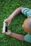 Little boy lying on grass looking at digital camera