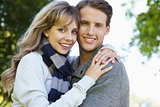 Cute couple embracing and smiling at camera in the park