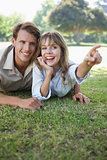 Carefree couple lying in the park with woman pointing