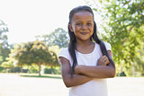 Little girl smiling at camera with arms crossed in the park