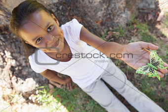 Little girl holding a butterfly in the park smiling at camera
