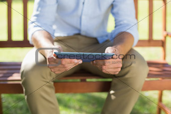 Man sitting on park bench using tablet