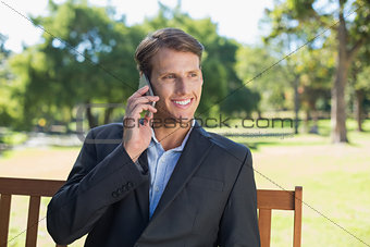 Casual businessman talking on phone on park bench