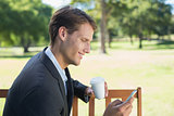 Casual businessman texting on phone on park bench