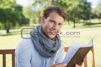 Stylish young man holding journal smiling at camera