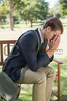 Worried businessman sitting on park bench