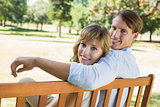 Couple relaxing on park bench together smiling at camera