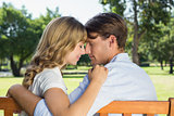 Couple relaxing on park bench together head to head