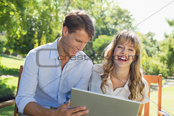Cute couple sitting on park bench together using laptop and laughing