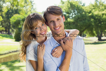 Cute couple smiling at camera together in the park