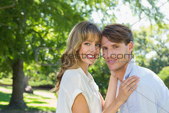 Cute couple hugging and smiling at camera in the park