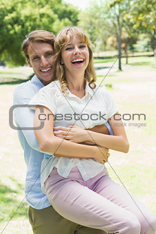 Handsome man picking up his laughing girlfriend in the park