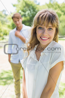 Beautiful blonde smiling at camera with boyfriend in background