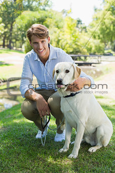 Handsome man with his labrador in the park smiling at camera