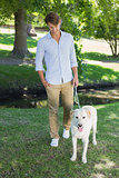 Handsome smiling man walking his labrador in the park