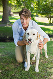 Handsome smiling man posing with his labrador in the park