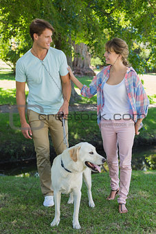 Happy couple walking with their labrador in the park