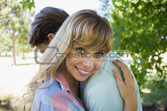 Loving young couple standing together in the park woman smiling at camera
