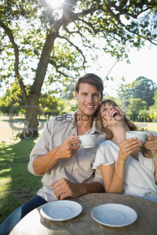 Laughing couple having tea outside in a cafe