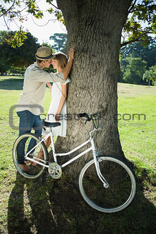 Cute couple leaning against tree in the park